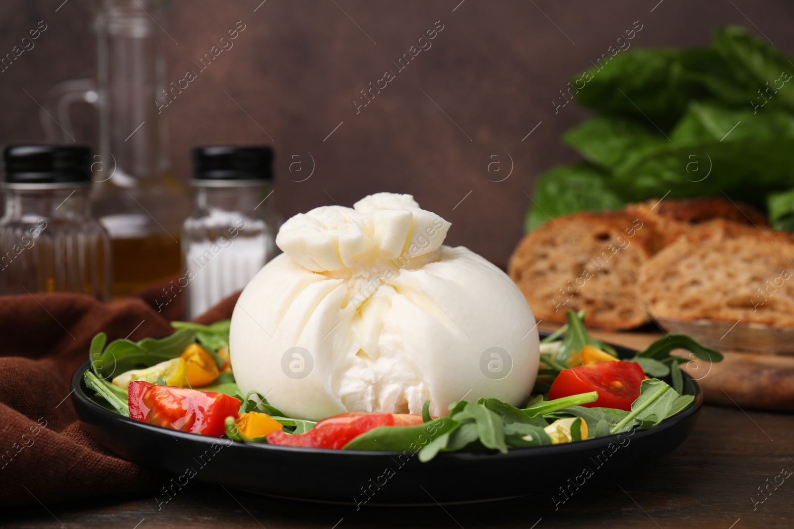 Photo of Delicious burrata salad on wooden table, closeup