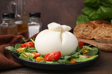 Photo of Delicious burrata salad on wooden table, closeup