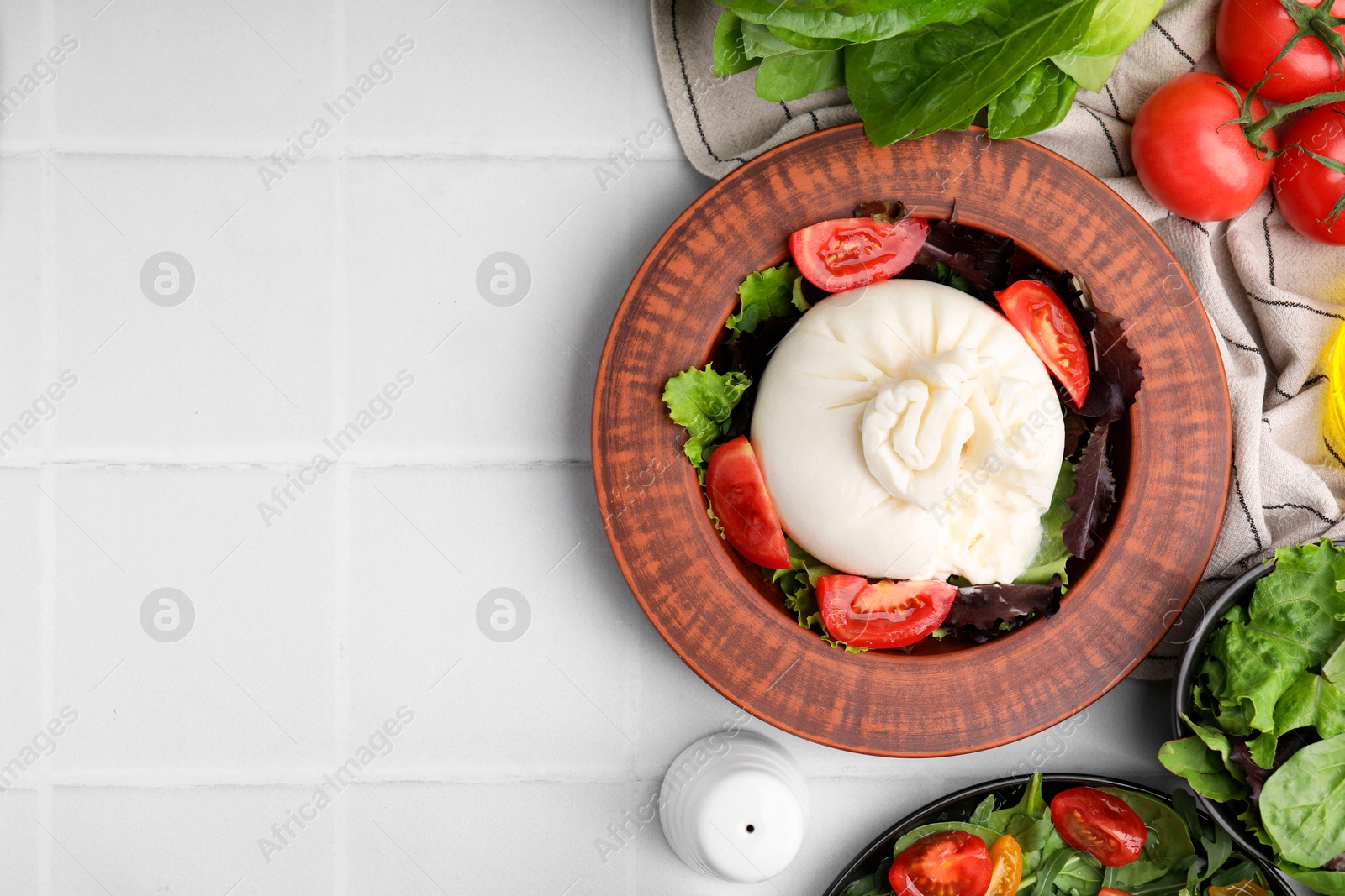 Photo of Delicious burrata salads in dishware on white tiled table, flat lay. Space for text