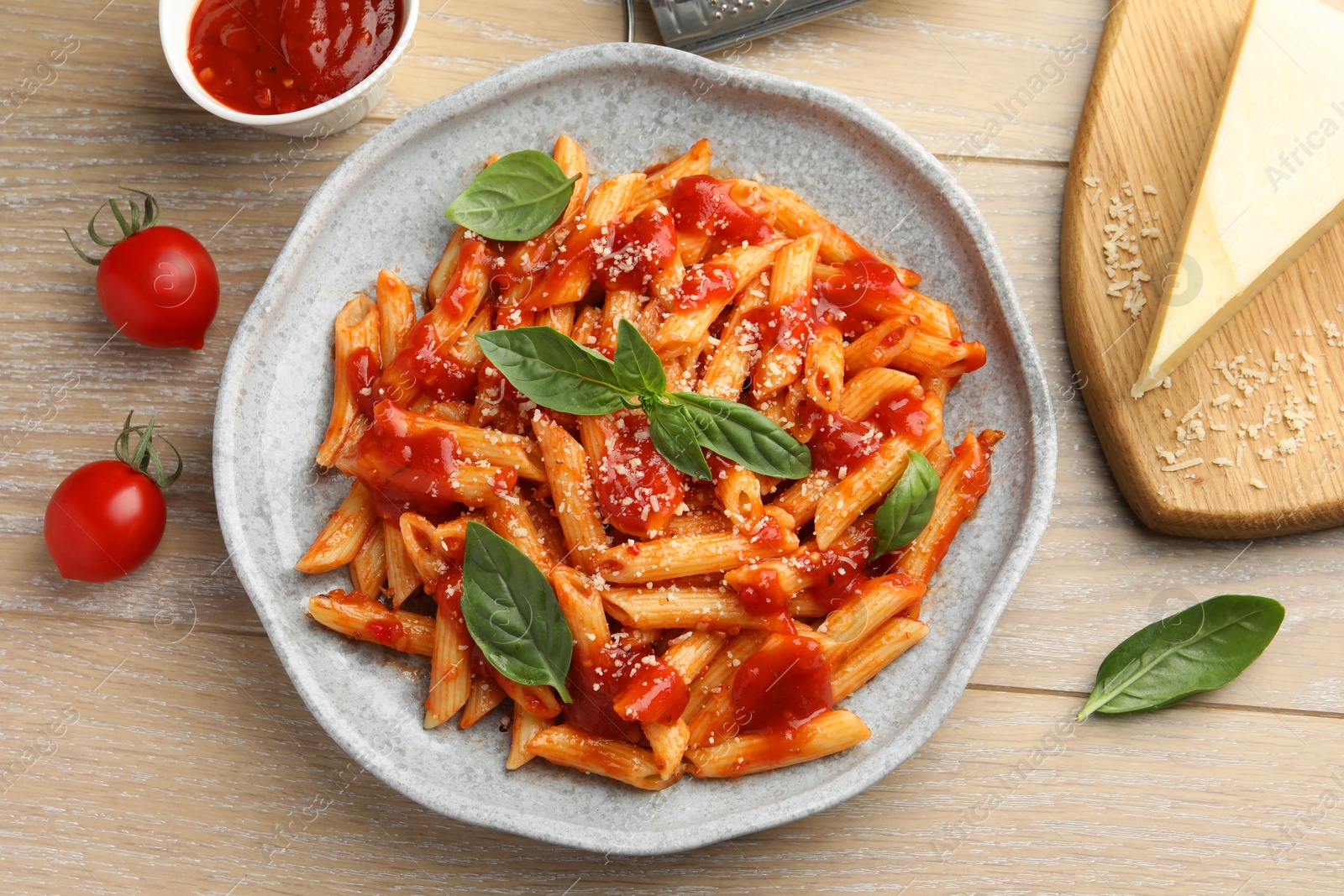 Photo of Delicious pasta with tomato sauce, basil and cheese on wooden table, flat lay