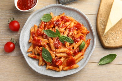 Photo of Delicious pasta with tomato sauce, basil and cheese on wooden table, flat lay