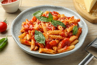 Photo of Delicious pasta with tomato sauce, basil and cheese on wooden table, closeup