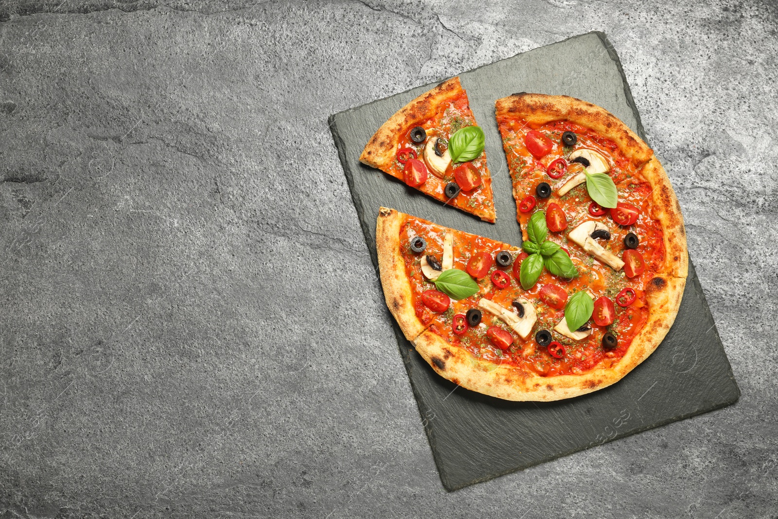 Photo of Tasty pizza with basil, olives and tomato on grey textured table, top view. Space for text