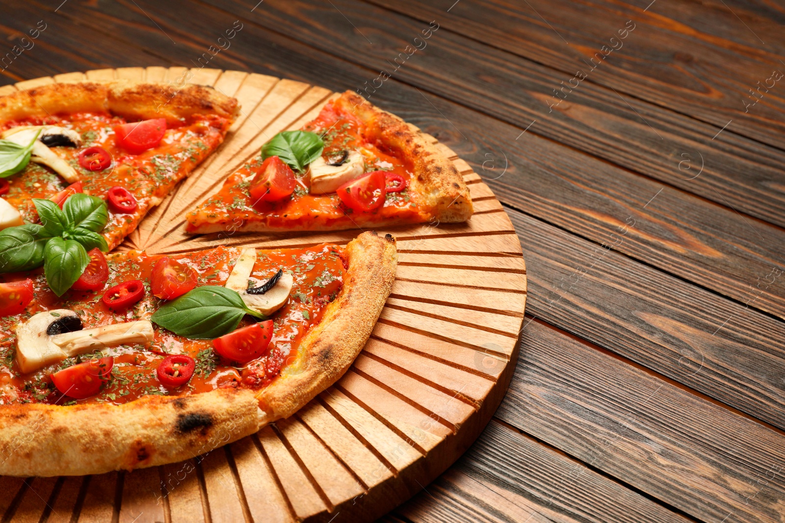 Photo of Tasty pizza with basil, mushrooms, chili pepper and tomato on wooden table, closeup. Space for text