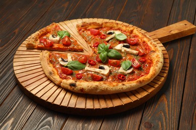 Tasty pizza with basil, mushrooms, chili pepper and tomato on wooden table, closeup