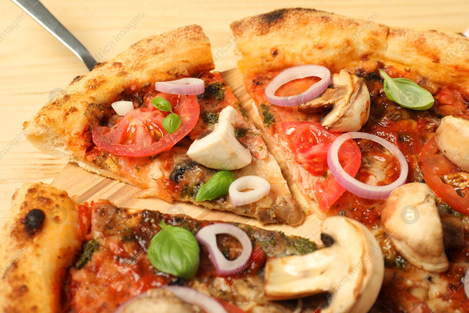 Photo of Tasty pizza with basil, mushrooms, onion and tomato on wooden table, closeup