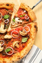 Photo of Tasty pizza with basil, mushrooms, onion and tomato on wooden table, top view