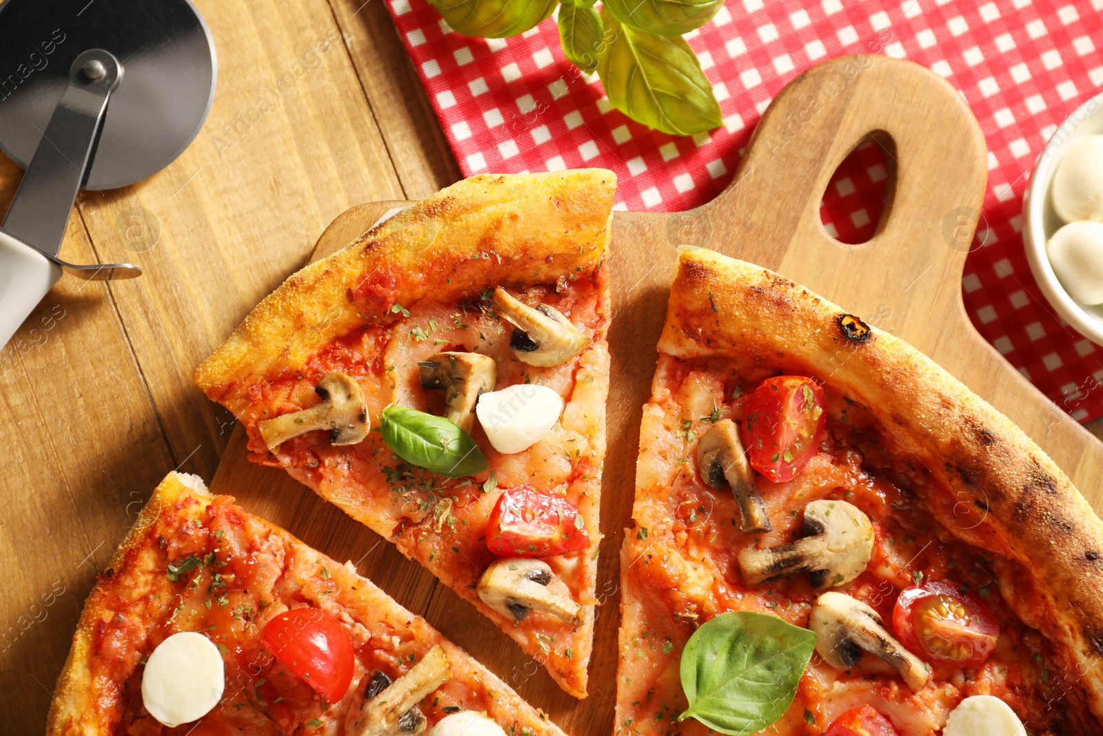 Photo of Tasty pizza with basil, mushrooms, mozzarella and tomato on wooden table, flat lay