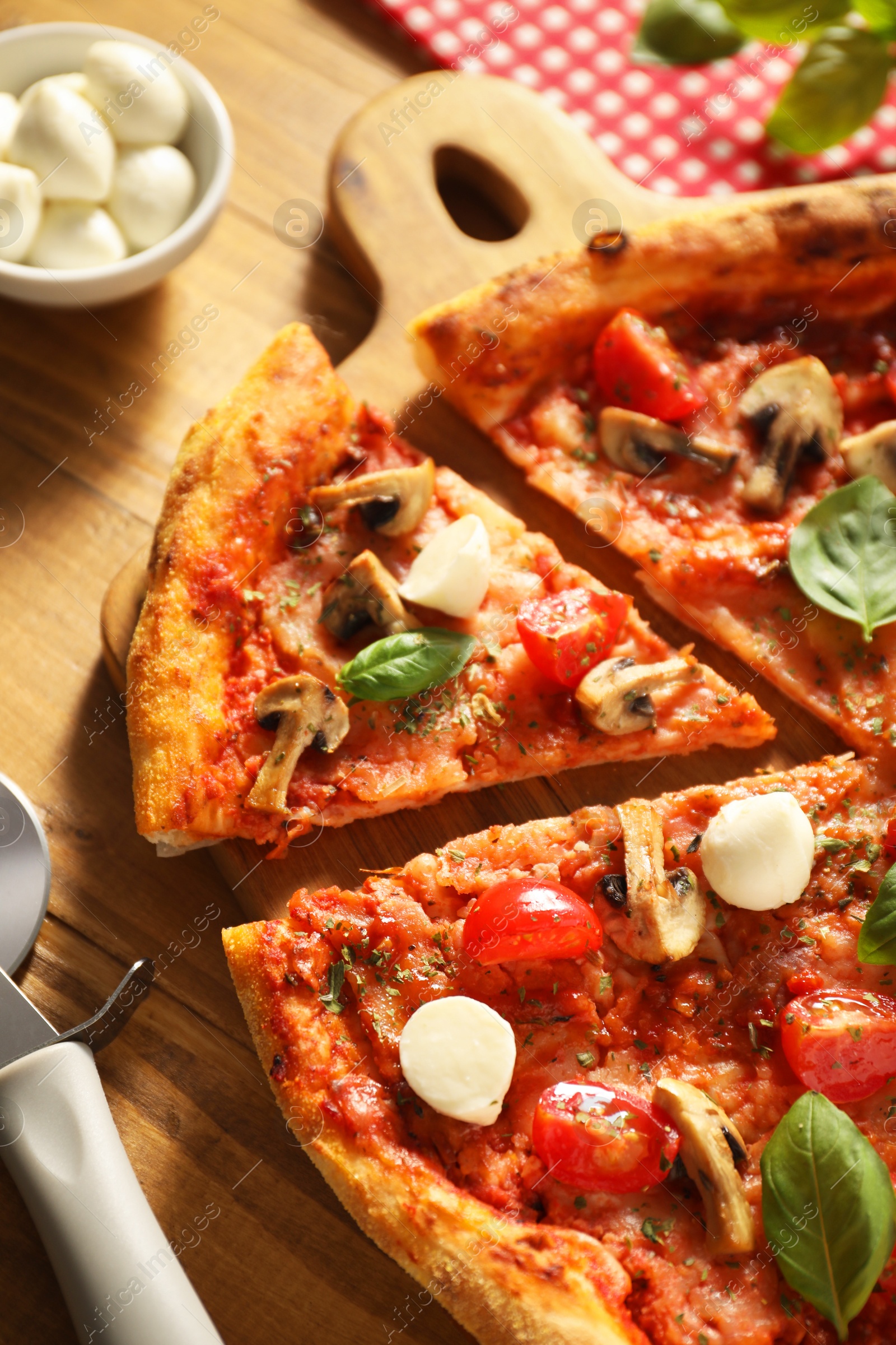 Photo of Tasty pizza with basil, mushrooms, mozzarella and tomato on wooden table, closeup