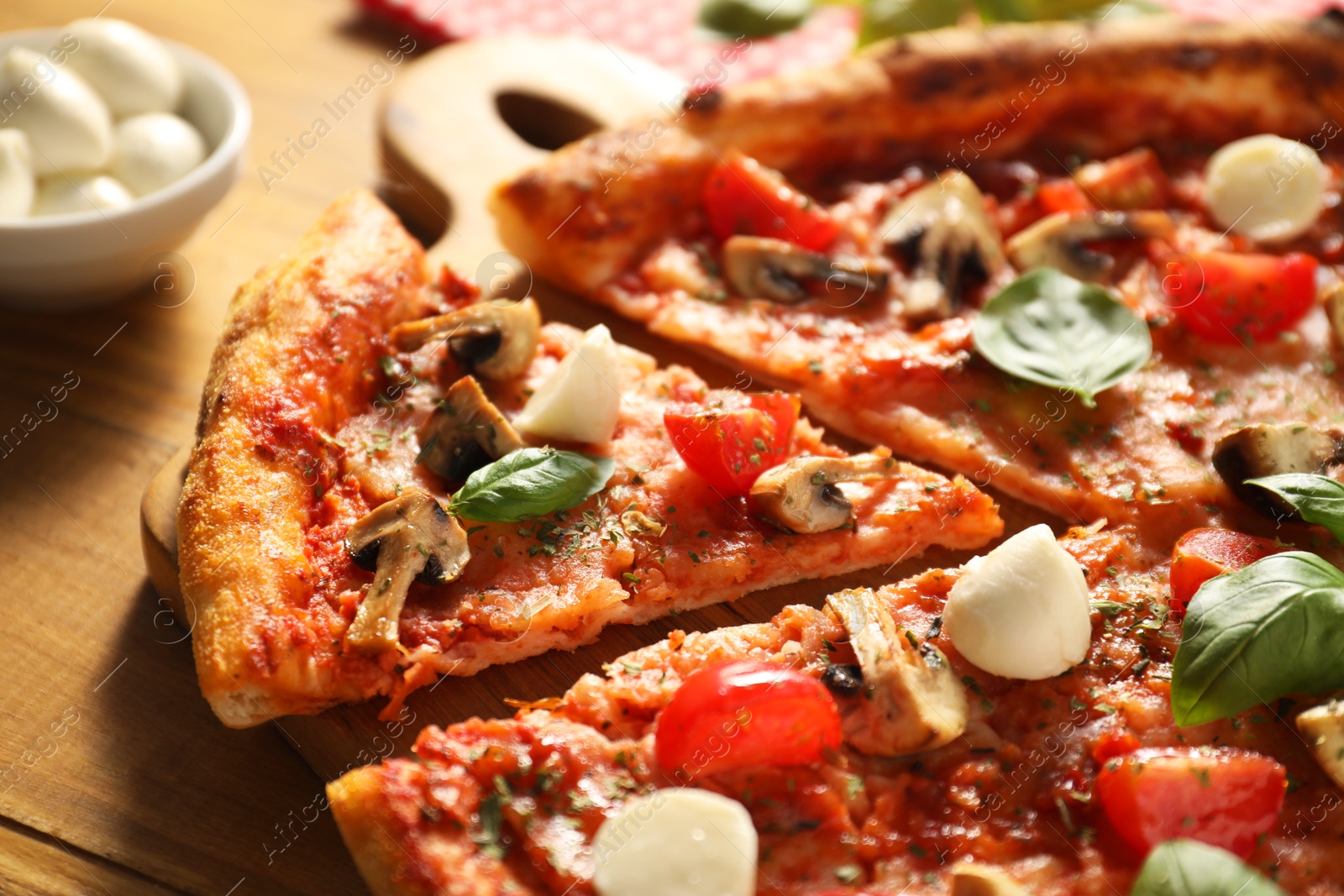 Photo of Tasty pizza with basil, mushrooms, mozzarella and tomato on wooden table, closeup