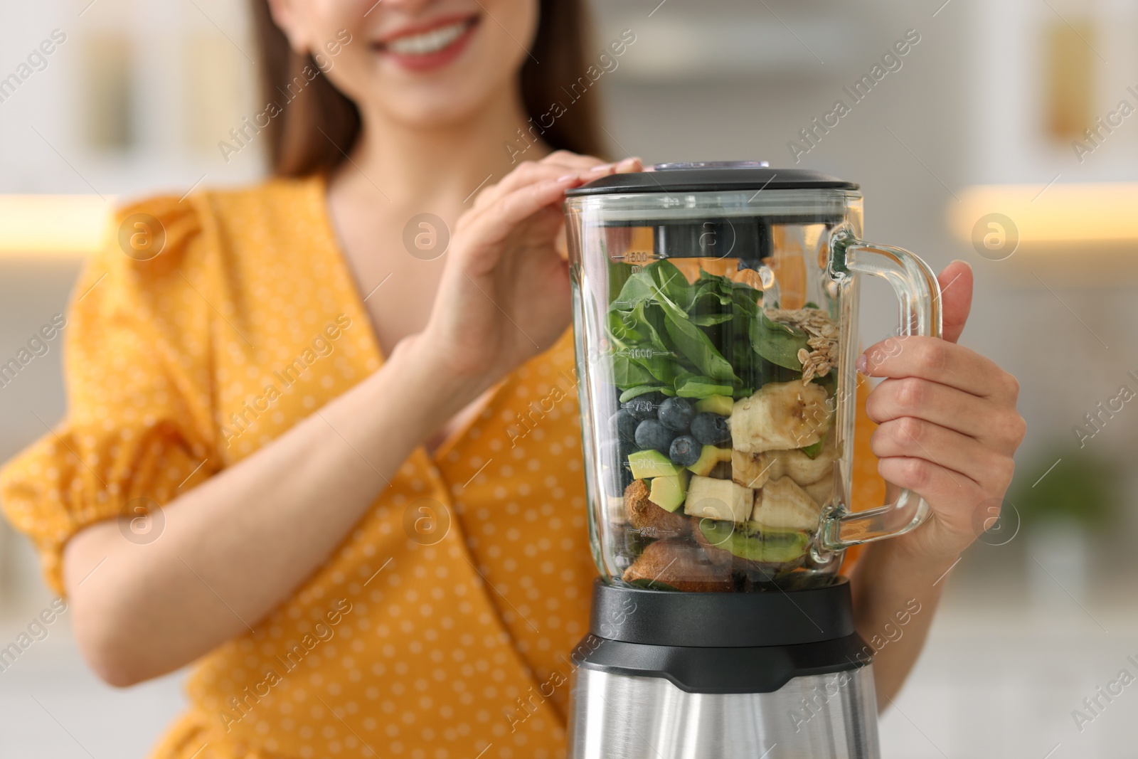 Photo of Woman making delicious smoothie with blender in kitchen, closeup