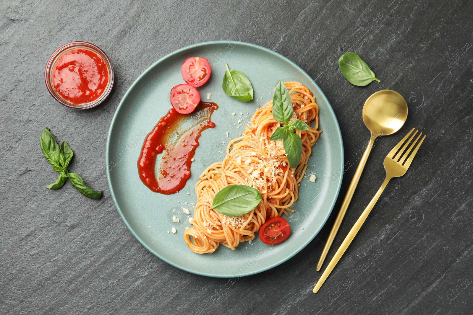 Photo of Delicious pasta with tomato sauce, basil and cheese served on black textured table, flat lay