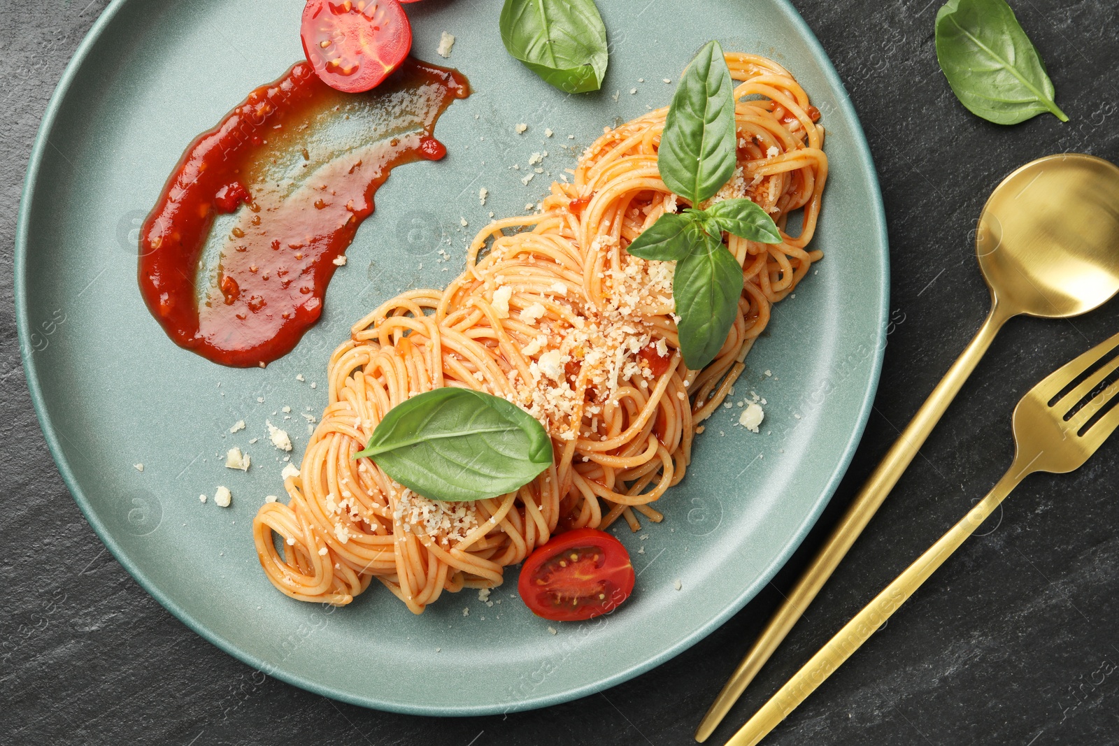 Photo of Delicious pasta with tomato sauce, basil and cheese served on black textured table, flat lay