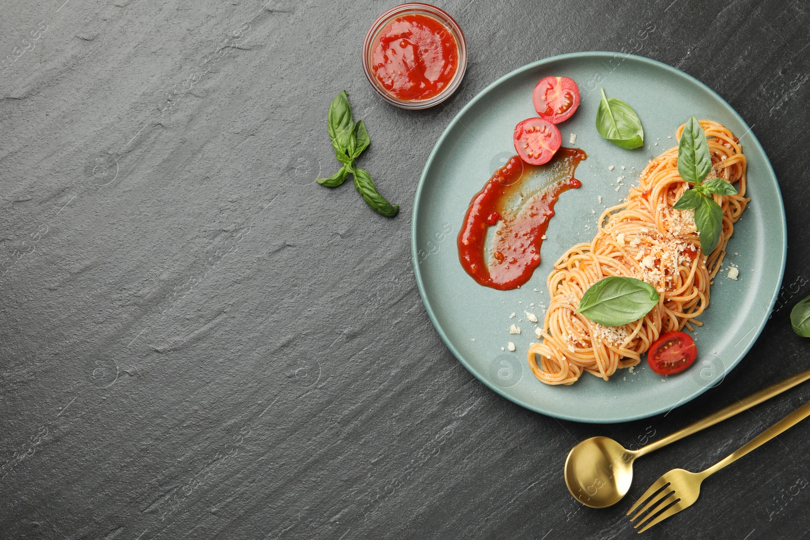 Photo of Delicious pasta with tomato sauce, basil and cheese served on black textured table, flat lay. Space for text