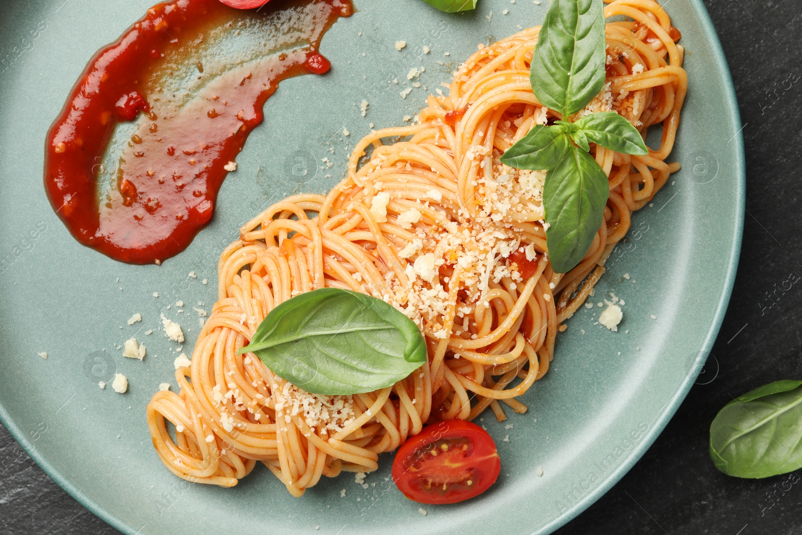 Photo of Delicious pasta with tomato sauce, basil and cheese on black table, top view