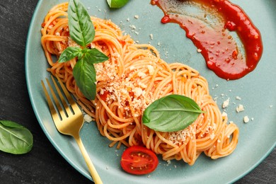 Photo of Delicious pasta with tomato sauce, basil and cheese served on black table, top view