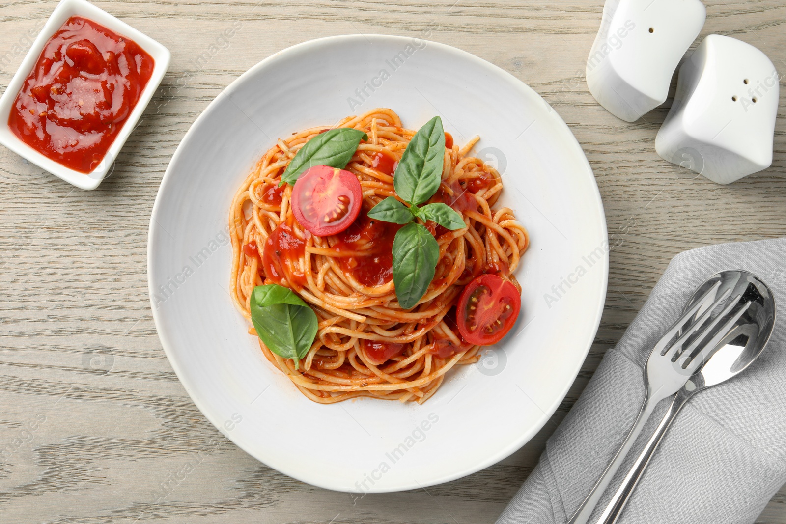 Photo of Delicious pasta with tomato sauce and basil in bowl served on wooden table, flat lay