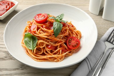 Photo of Delicious pasta with tomato sauce and basil in bowl served on wooden table, closeup