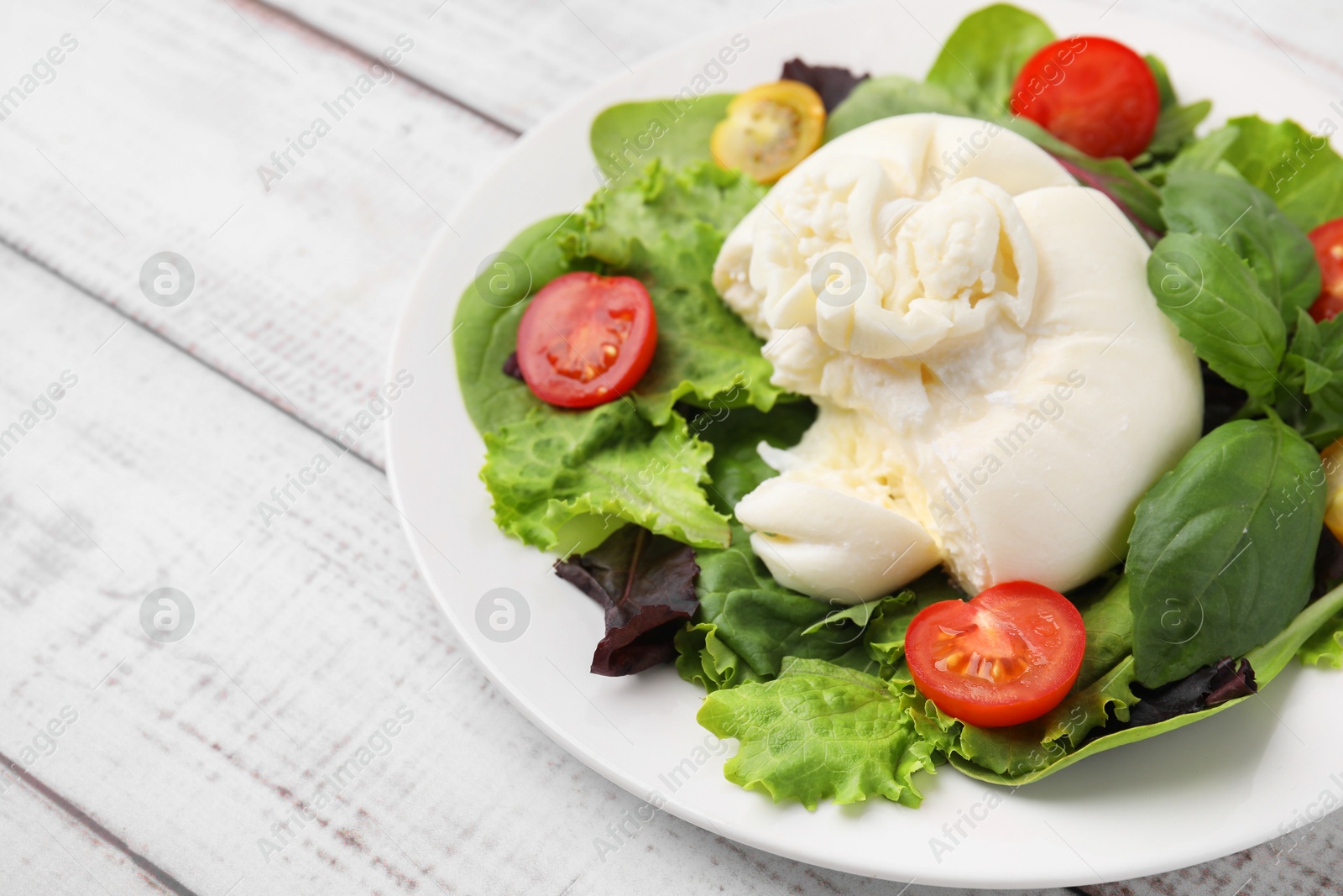 Photo of Delicious fresh burrata salad on white wooden table. Space for text