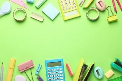 Photo of Bright staplers and other stationery on green background, flat lay. Space for text