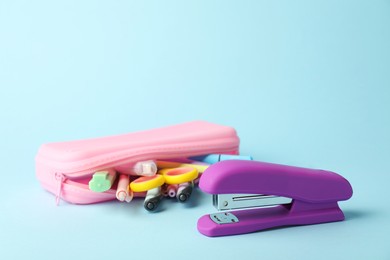 Photo of Violet stapler and other stationery on light blue background, closeup