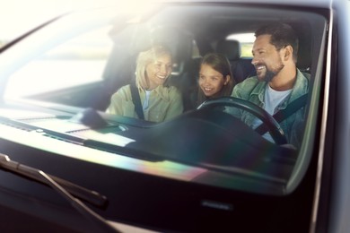 Happy family enjoying trip together by car, view through windshield