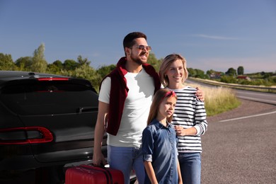 Happy family with red suitcase near car outdoors