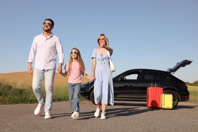 Parents, their daughter, car and suitcases outdoors. Family traveling