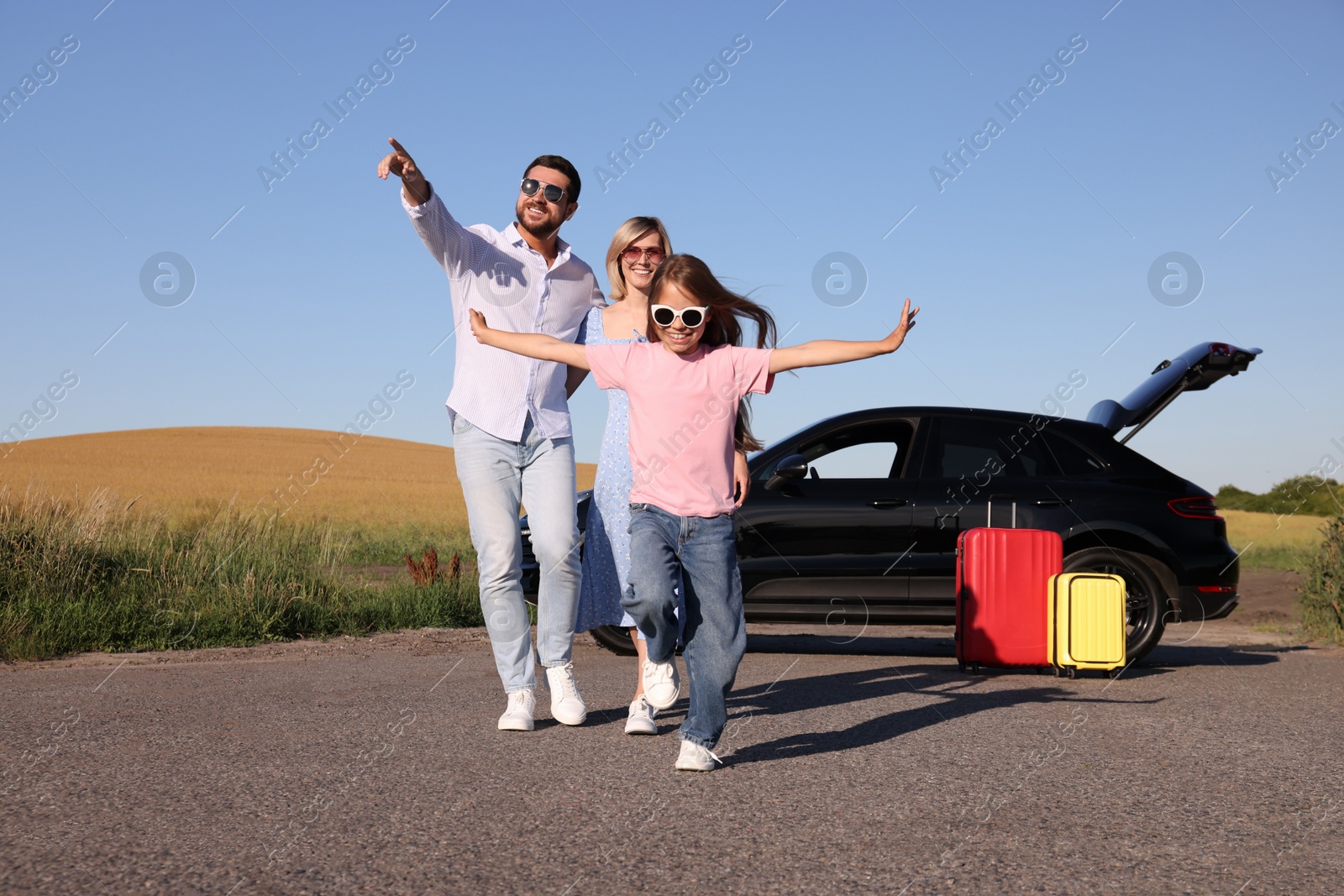 Photo of Parents, their daughter, car and suitcases outdoors. Family traveling