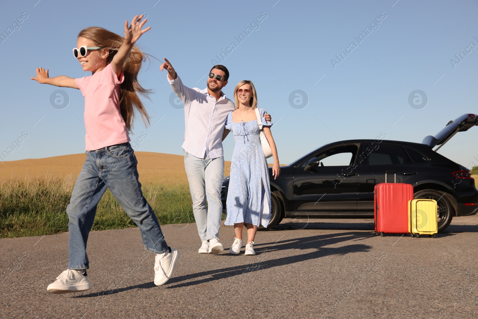 Photo of Parents, their daughter, car and suitcases outdoors. Family traveling