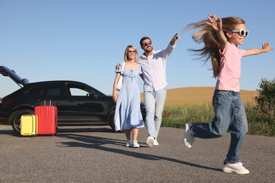 Parents, their daughter, car and suitcases outdoors. Family traveling