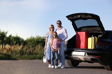 Happy family near car with suitcases outdoors, space for text