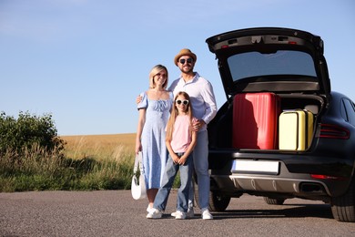 Happy family near car with suitcases outdoors, space for text