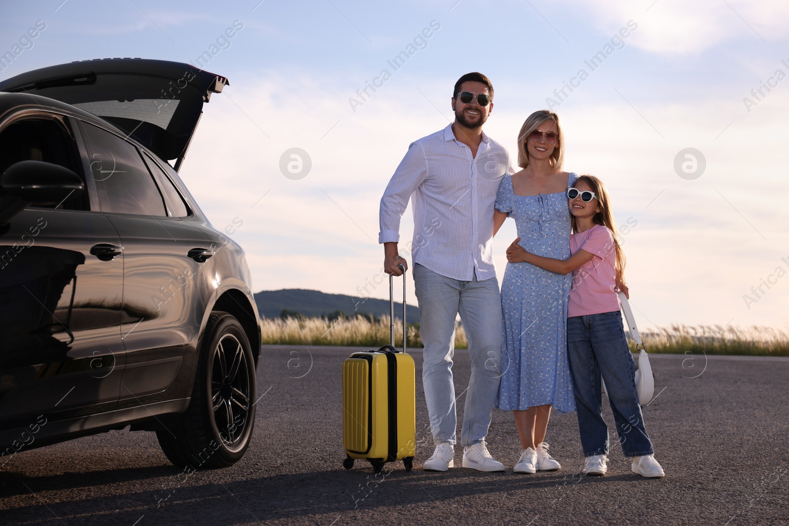 Photo of Happy family with suitcase near car outdoors