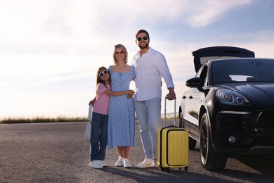 Photo of Happy family with suitcase near car outdoors, space for text
