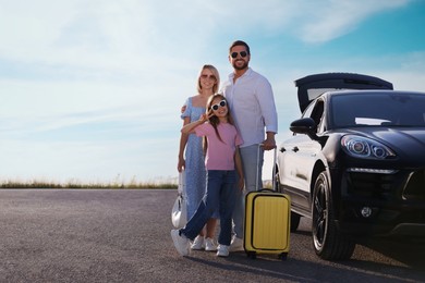 Photo of Happy family with suitcase near car outdoors, space for text