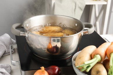 Photo of Boiling potatoes in metal pot on stove