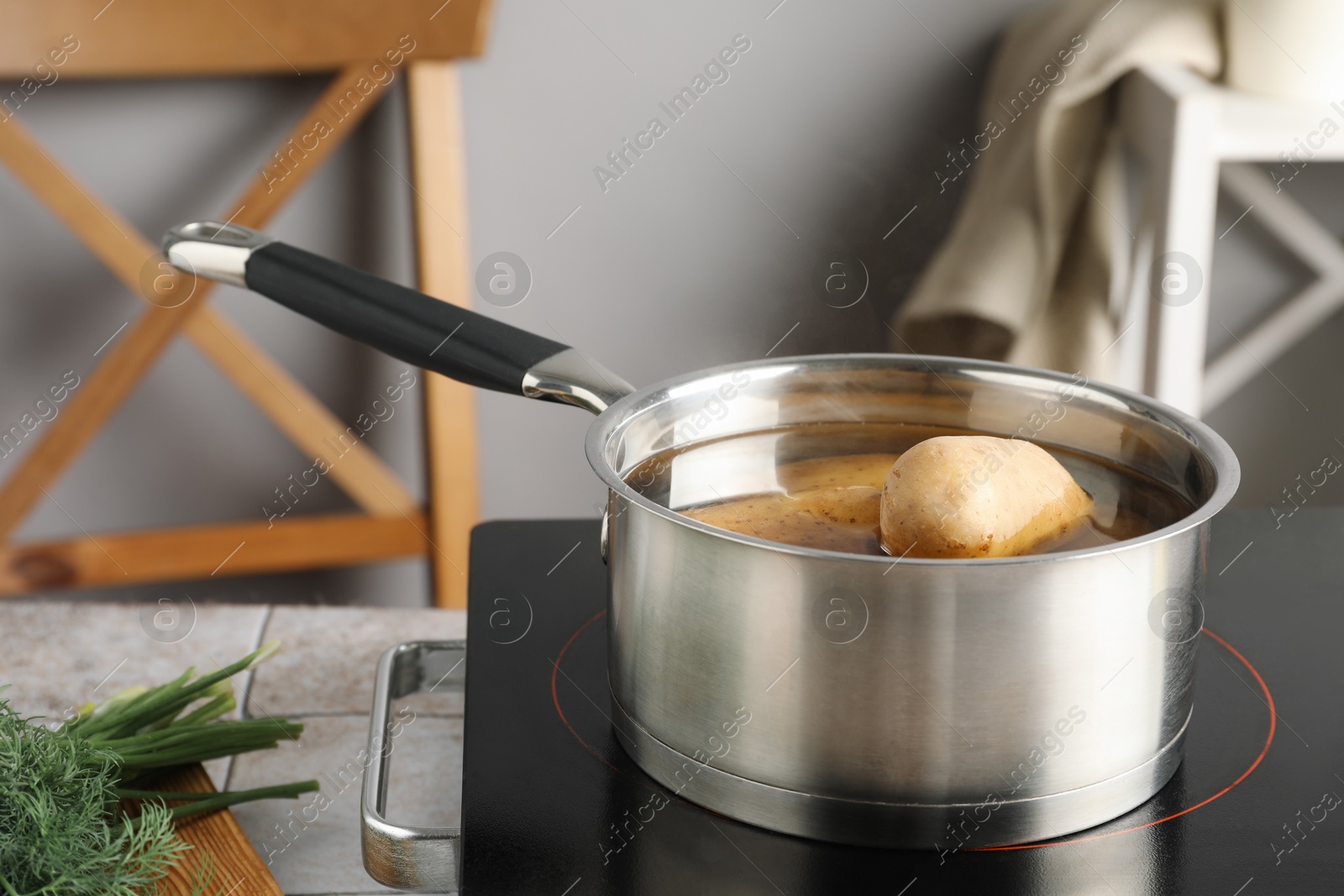 Photo of Boiling potatoes in saucepan on stove in kitchen