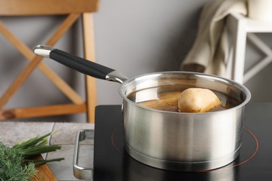 Boiling potatoes in saucepan on stove in kitchen