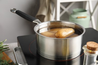 Boiling potatoes in saucepan on stove in kitchen