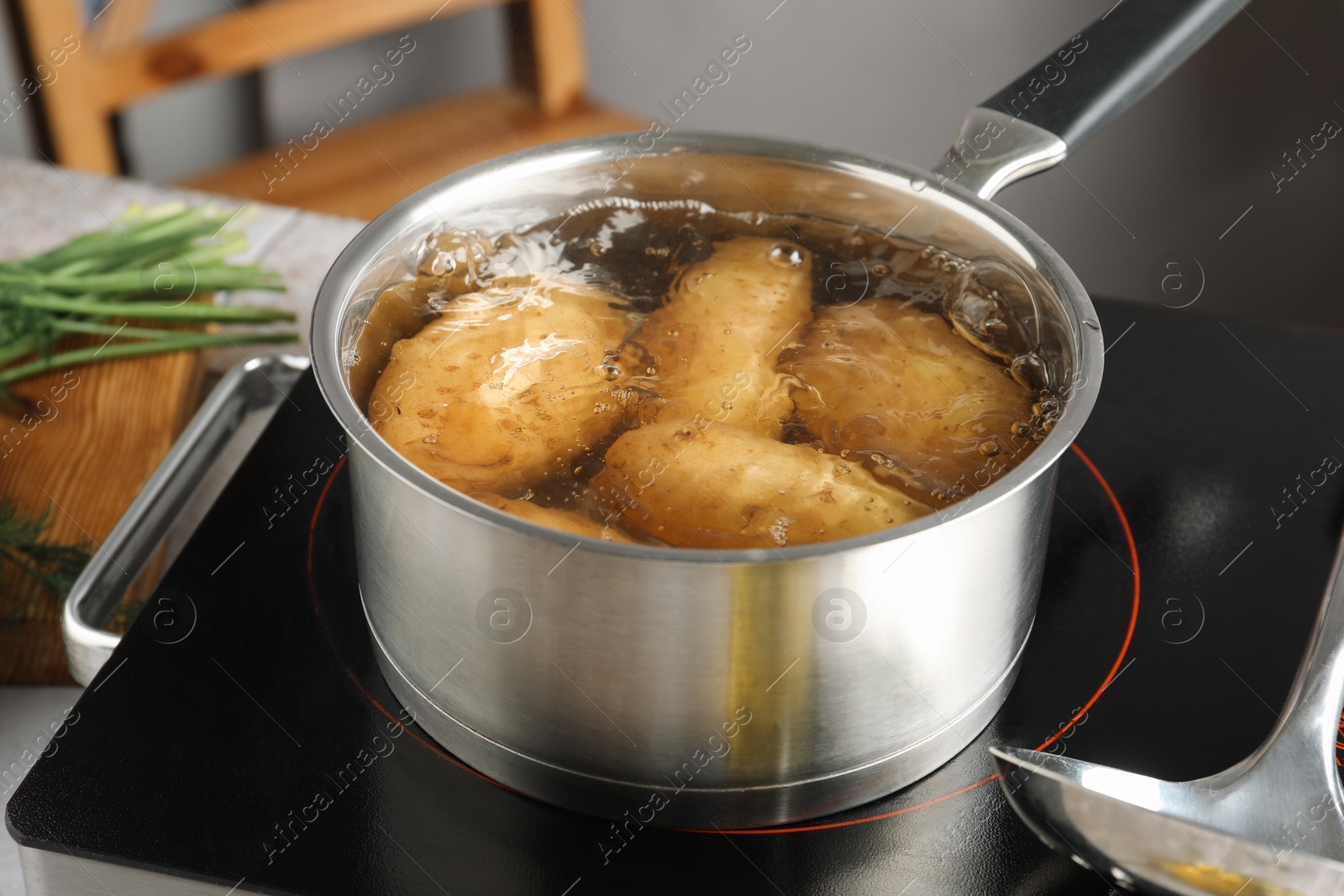 Photo of Boiling potatoes in saucepan on stove in kitchen