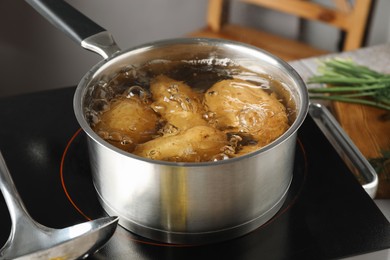 Photo of Boiling potatoes in saucepan on stove in kitchen