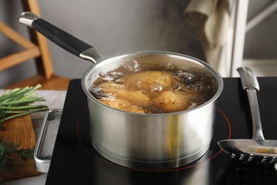 Boiling potatoes in saucepan on stove in kitchen