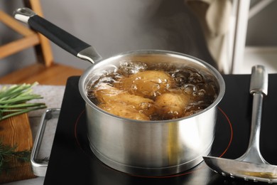 Boiling potatoes in saucepan on stove in kitchen