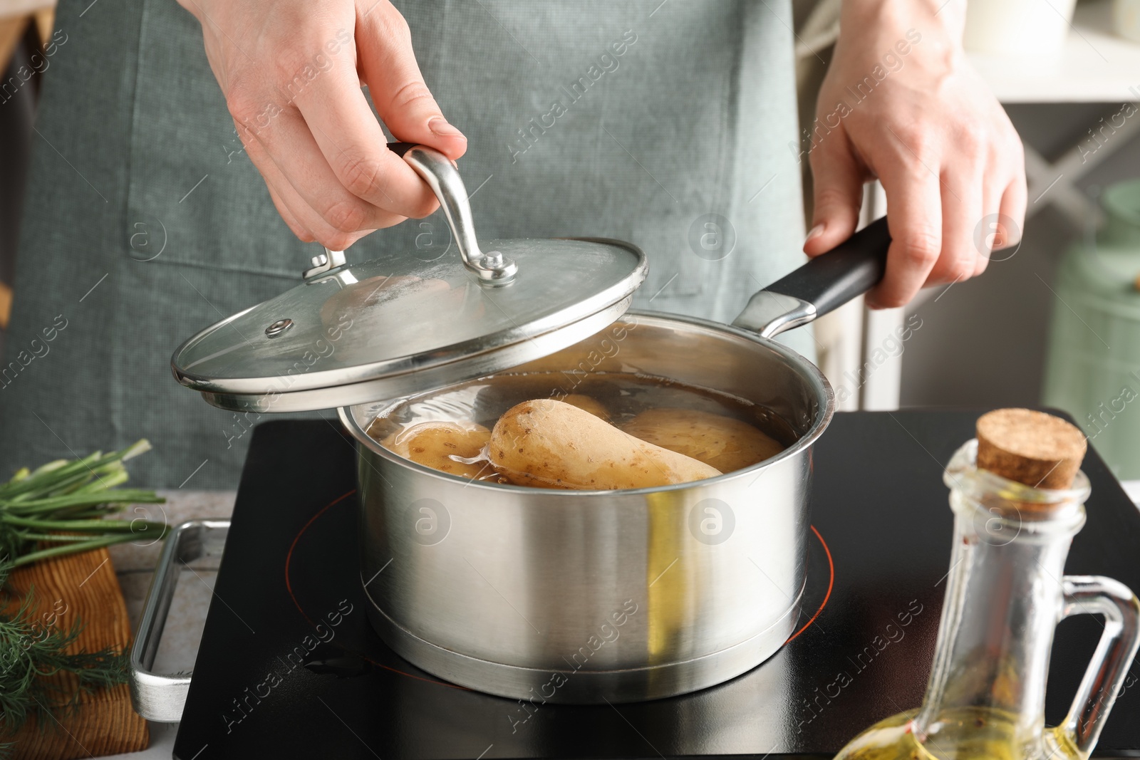 Photo of Woman boiling potatoes in saucepan on stove, closeup