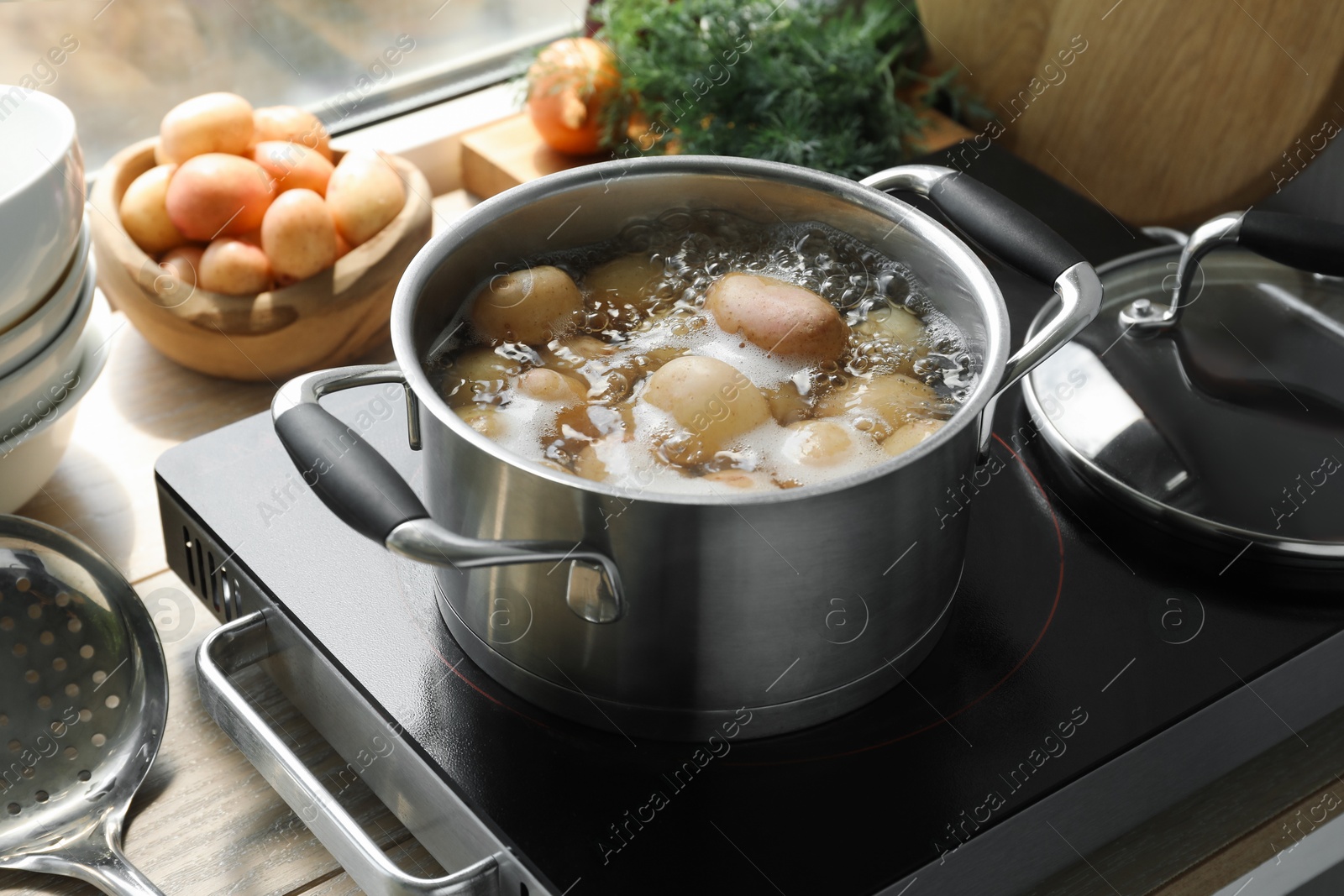 Photo of Boiling potatoes in pot on stove in kitchen