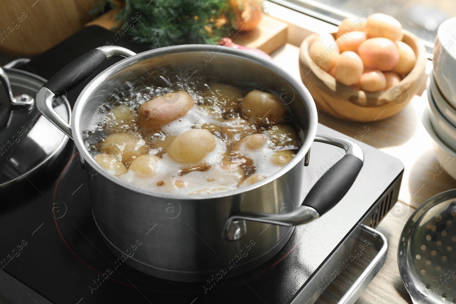 Photo of Boiling potatoes in pot on stove in kitchen