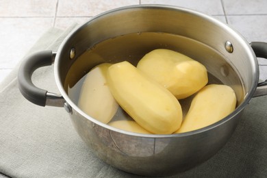 Photo of Raw potatoes in pot with water on table