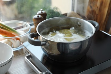 Photo of Boiling potatoes in pot on stove in kitchen