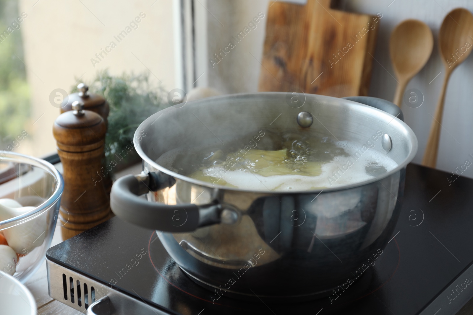 Photo of Boiling potatoes in pot on stove in kitchen